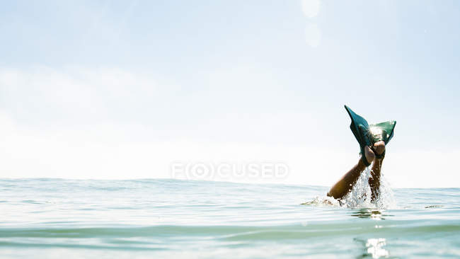 Imagem cortada de pernas masculinas com nadadeiras saindo do mar — Fotografia de Stock