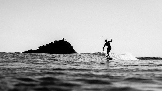 Silhueta de um homem surfando na onda no oceano — Fotografia de Stock