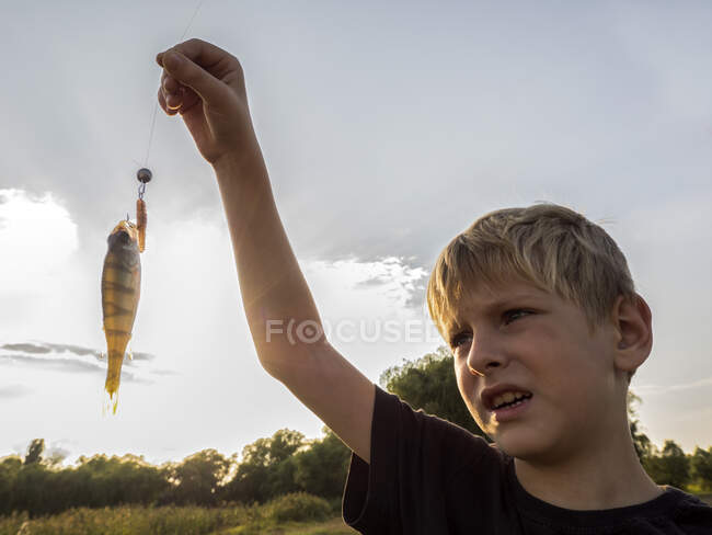 Boy demonstrates caught them on a spinning perch on sky background — Stock Photo