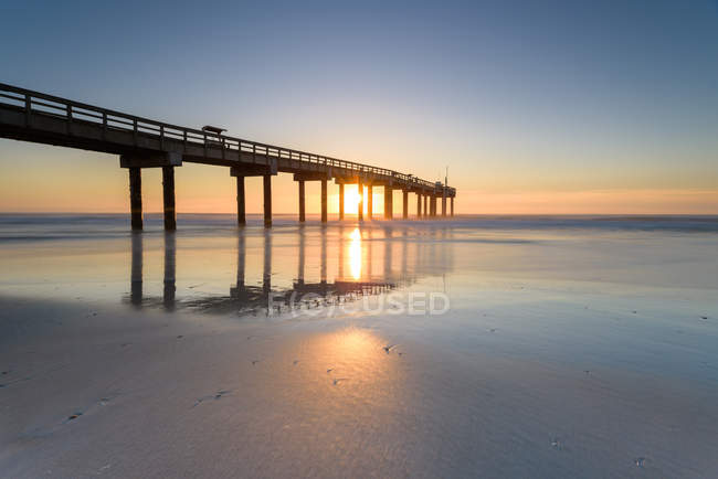 Magnifique coucher de soleil ciel et jetée sur l'eau de mer — Photo de stock