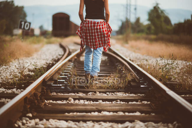 Menina andando na estrada de ferro visto de volta — Fotografia de Stock