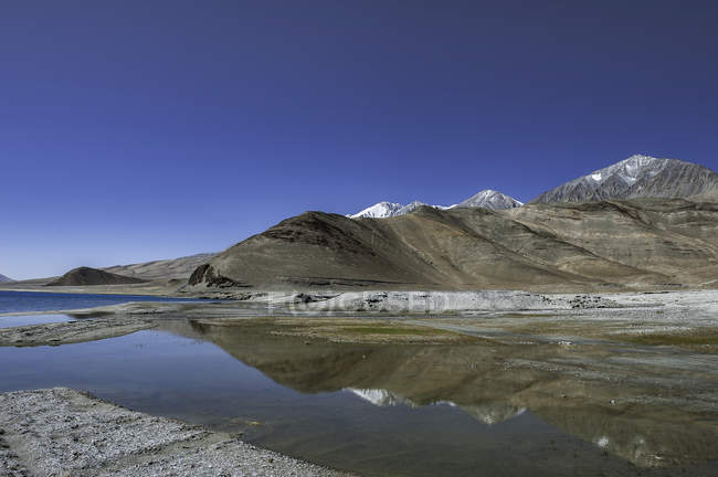 Mountains and lake water with sky reflection — Stock Photo