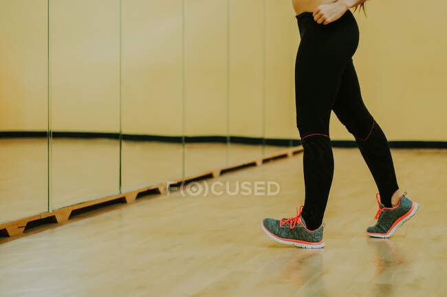 Chica en la sala de fitness de pie delante de un espejo - foto de stock