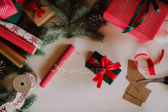 Weihnachtshintergrund mit Geschenken, Tannenzweige, rote Schleife, Geschenkboxen, Draufsicht — Stockfoto
