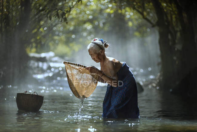 Old women fishing in river — Stock Photo
