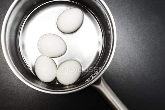 Saucepan of eggs in water, overhead view — Stock Photo