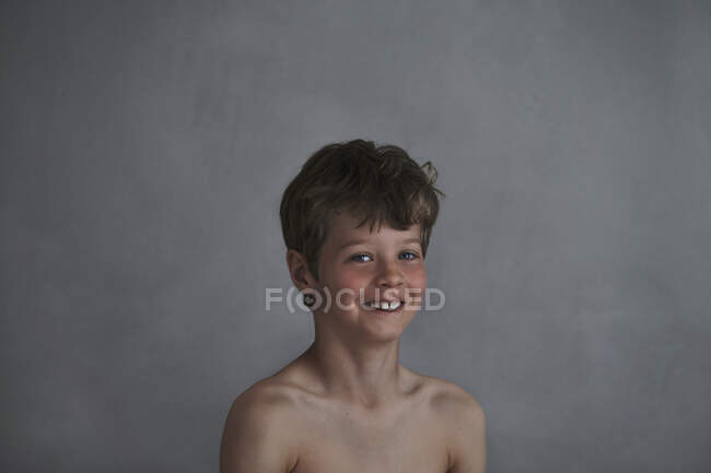 Portrait d'un garçon souriant sur fond gris — Photo de stock
