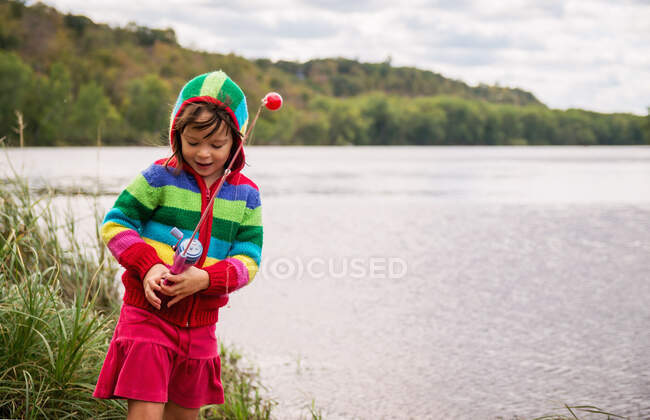 Adorável menina em pé à beira do rio pesca — Fotografia de Stock