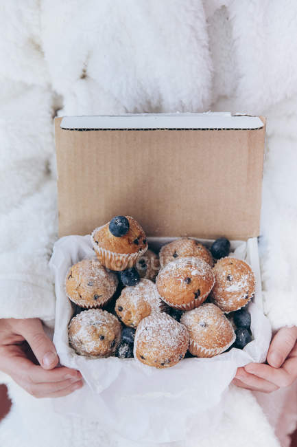 Girl holding box of blueberry muffins — Stock Photo