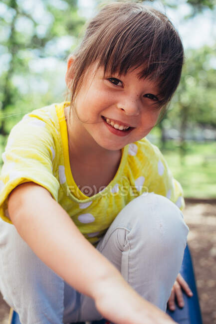 Портрет улыбающейся девушки, сидящей на горке — стоковое фото