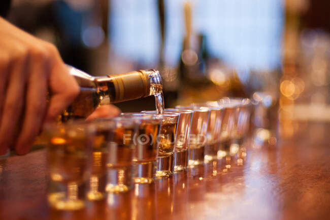 Person pouring a line of shots in a bar — Stock Photo