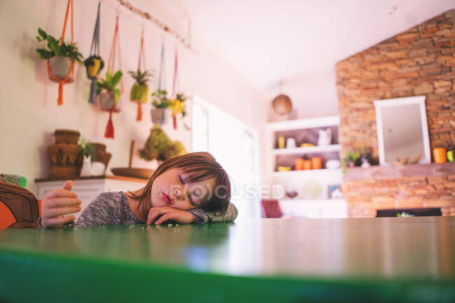 Chica durmiendo en la mesa de la cocina - foto de stock