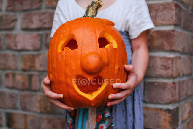 Girl holding carved pumpkin with heart shape mouth — Stock Photo