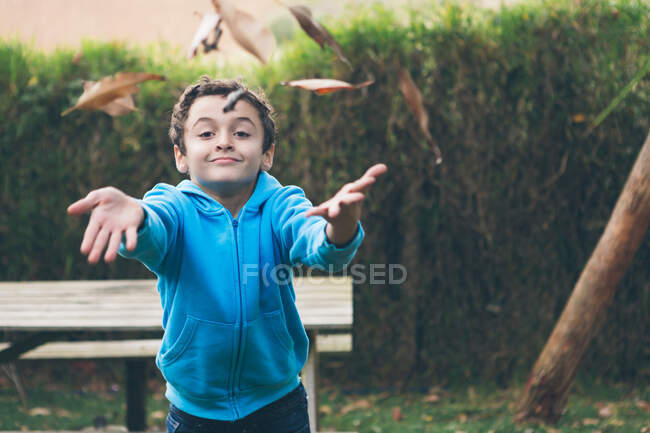 Хлопчик кидає осіннє листя в повітрі — стокове фото