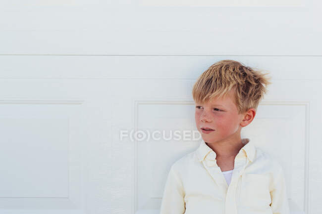 Портрет мальчика перед деревянной белой дверью — стоковое фото