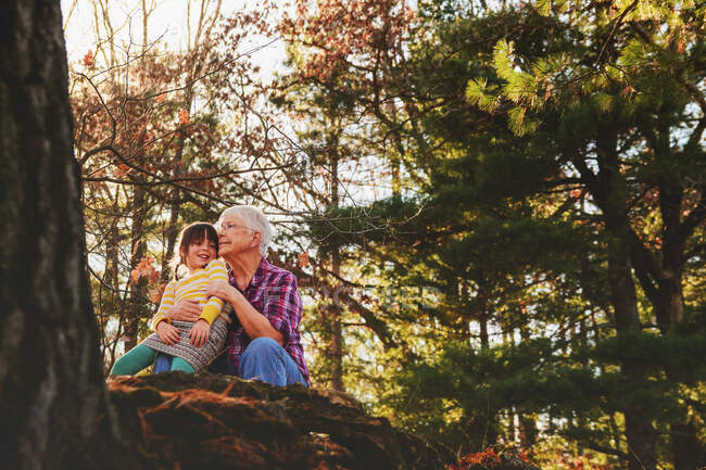 Бабуся і онука сидять в лісі обіймаючись — стокове фото