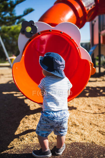 Мальчик, стоящий у горки на детской площадке — стоковое фото