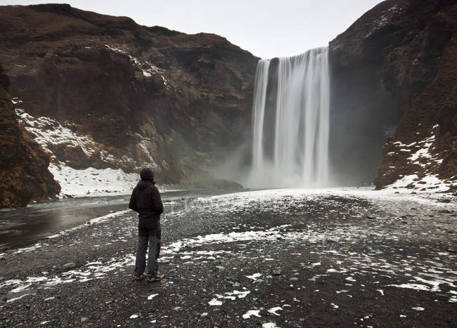 Mann blickt auf skogafoss Wasserfall, Island — Stockfoto