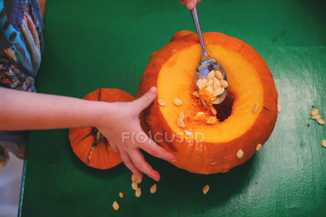 Girl removing seeds from a pumpkin — Stock Photo