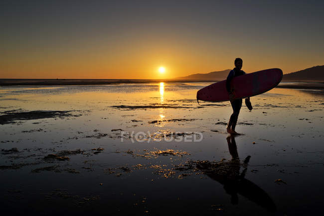 Силуэт человека с доской для серфинга на пляже Лос-Лансес, Испания — стоковое фото