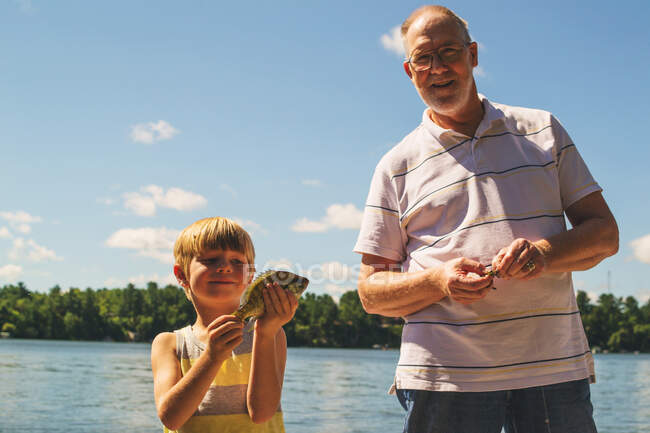 Grandfather and grandson with freshly caught fish — Stock Photo