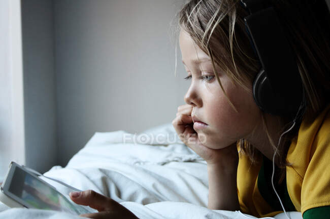 Niño usando auriculares usando tableta digital - foto de stock