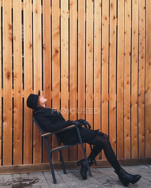 Frau sitzt auf einem Stuhl und lehnt sich zurück — Stockfoto