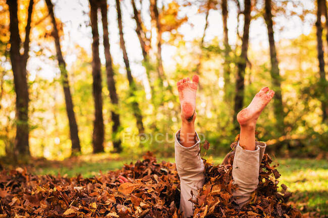 Ragazzo che gioca in foglie d'autunno — Foto stock
