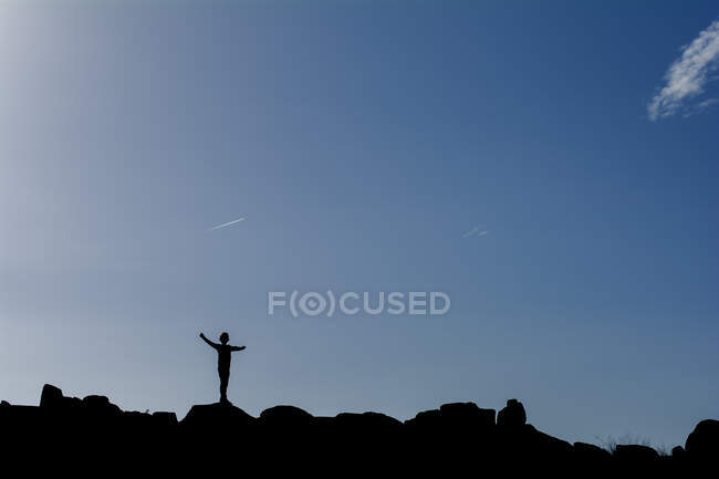 Silhouette di un ragazzo in piedi su rocce — Foto stock