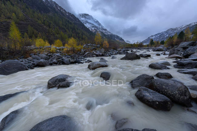 Vista panoramica del fiume che scorre attraverso la valle sotto la pioggia, Svizzera — Foto stock