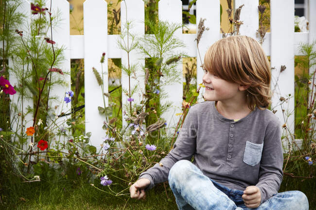 Sonriente niño sentado en un jardín al aire libre - foto de stock