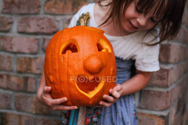 Girl holding carved pumpkin with heart shape mouth — Stock Photo