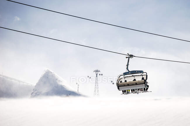 Cuatro esquiadores sentados en un telesilla, Kitzsteinhorn, Salzburgo, Austria - foto de stock