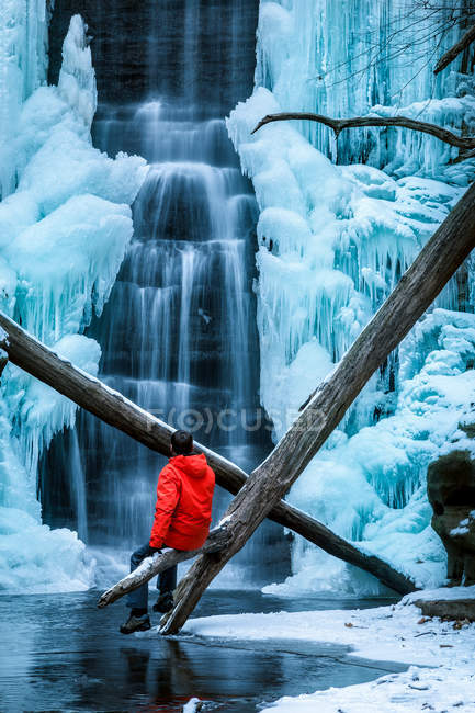 Homem sentado por cachoeira congelada, Matthiessen State Park, Illinois, América, EUA — Fotografia de Stock