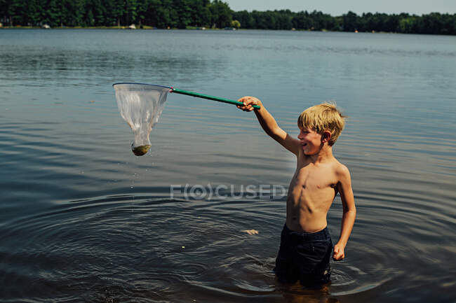 Ragazzo cattura di un pesce con una rete da pesca — Foto stock