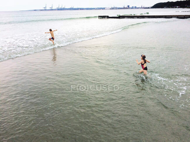 Мальчик и девочка бегут в море, Дания — стоковое фото