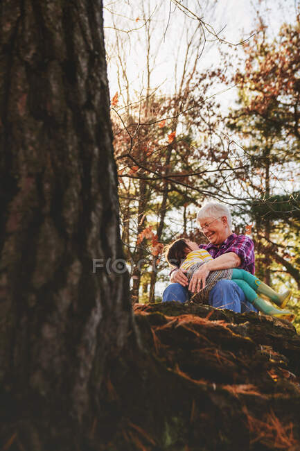 Бабуся з внучкою сидять на обіймах лісу. — стокове фото