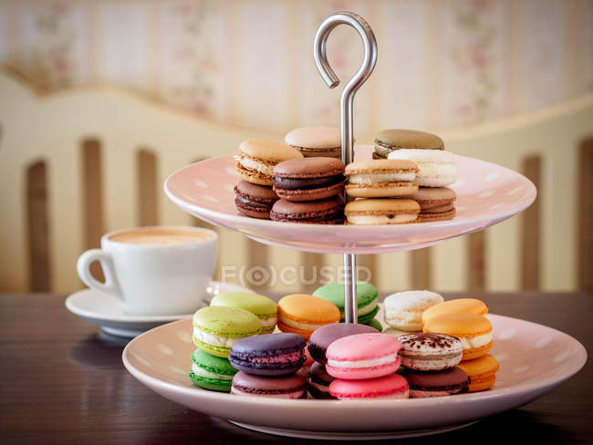 Seleção de macaroons no carrinho de bolo com cappuccino — Fotografia de Stock