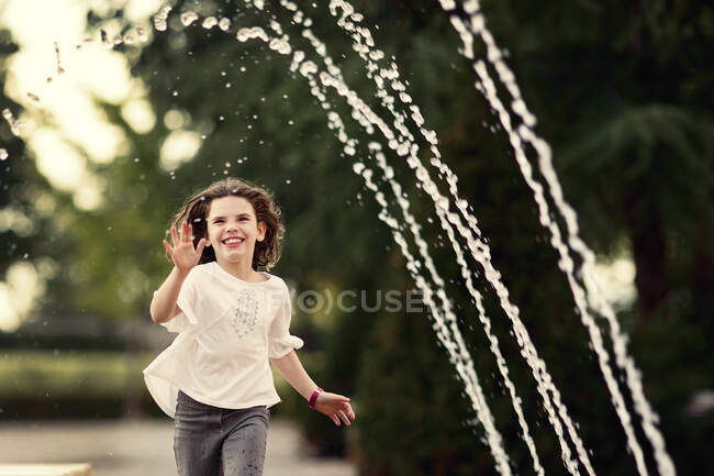 Дівчинка грає біля водних фонтанів на природі. — стокове фото
