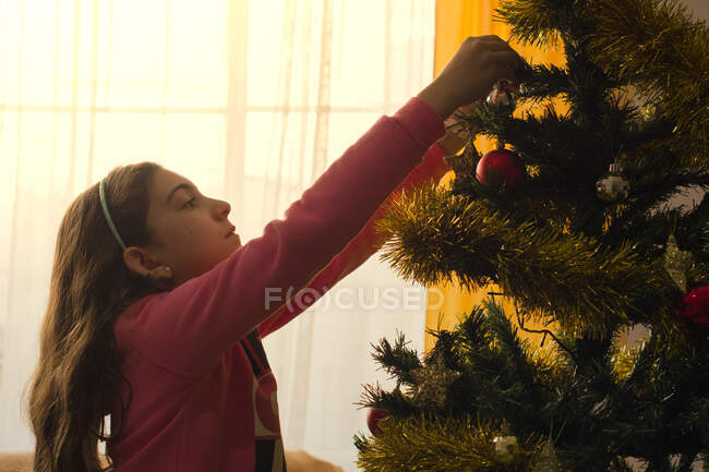 Menina decorando uma árvore de Natal em casa — Fotografia de Stock