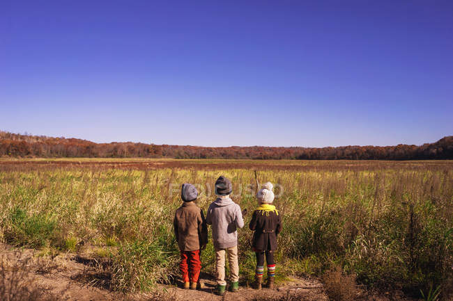 Tre bambini in piedi in un prato — Foto stock