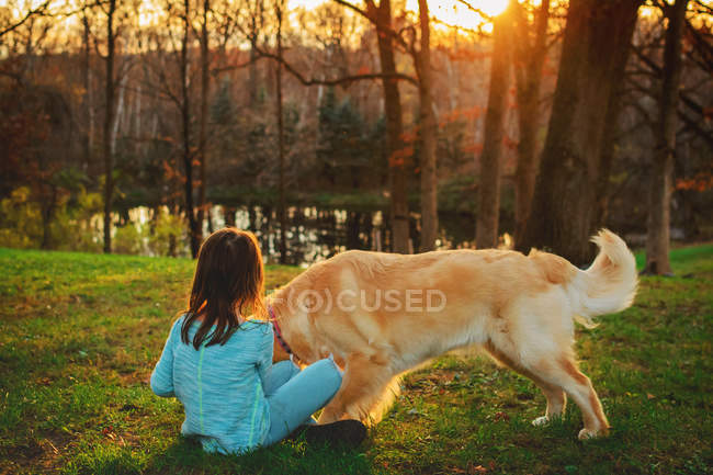 Chica joven y perro retriever de oro jugando en el jardín - foto de stock