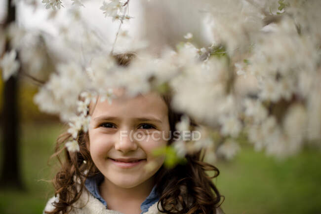 Portrait of a girl standing by apple blossom tree — Stock Photo