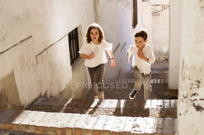 Niño y niña corriendo escaleras arriba, Granada, andalucia, España - foto de stock