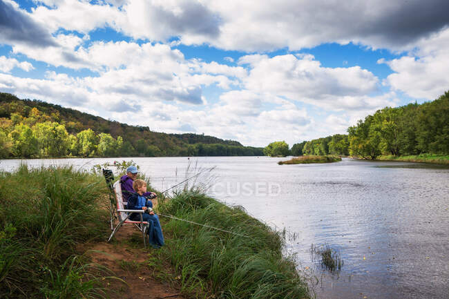 Mädchen und Großmutter sitzen am Fluss beim Angeln — Stockfoto