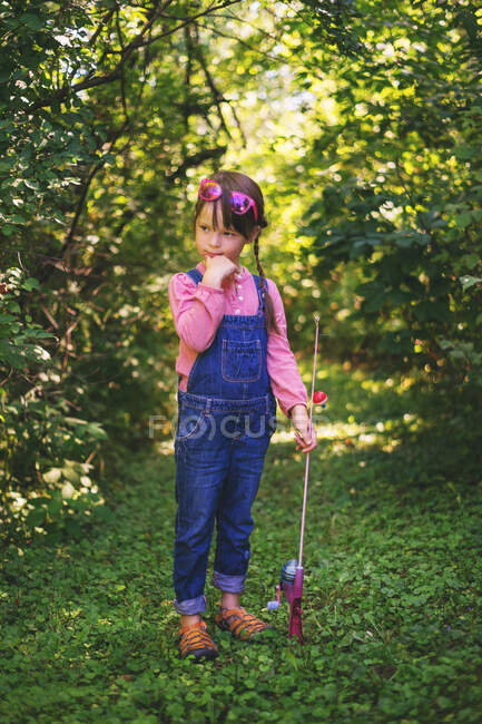 Girl standing in forest with fishing rod — Stock Photo