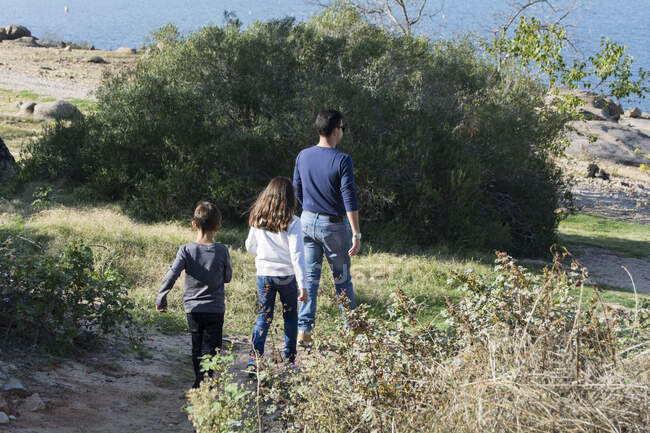 Vater und zwei Kinder spazieren in ländlicher Landschaft — Stockfoto
