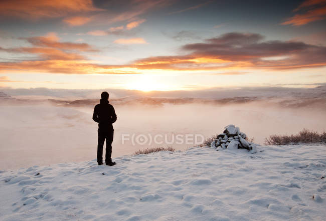 Вид сзади на человека, стоящего в зимнем пейзаже, Исландия — стоковое фото