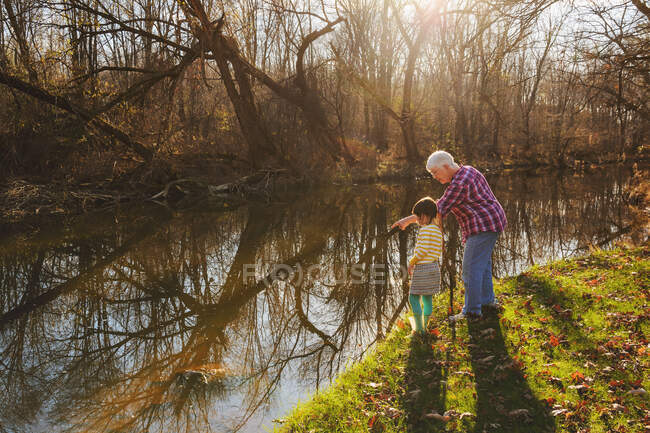 Бабуся вказує на річку зі своєю онукою — стокове фото