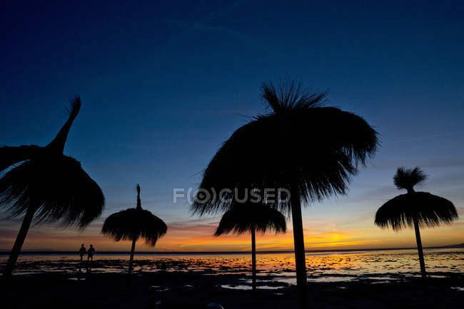 Silhouette of two people and parasols on Los Lances Beach, Tarifa, Cadiz, Andaulcia, Spain — Stock Photo